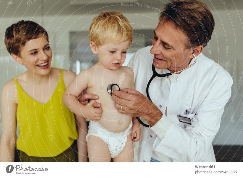 Pediatrician examining toddler with stethoscope, mother standing next to them Auscultation auscultate auscultating baby boys male laughing Laughter pediatrician