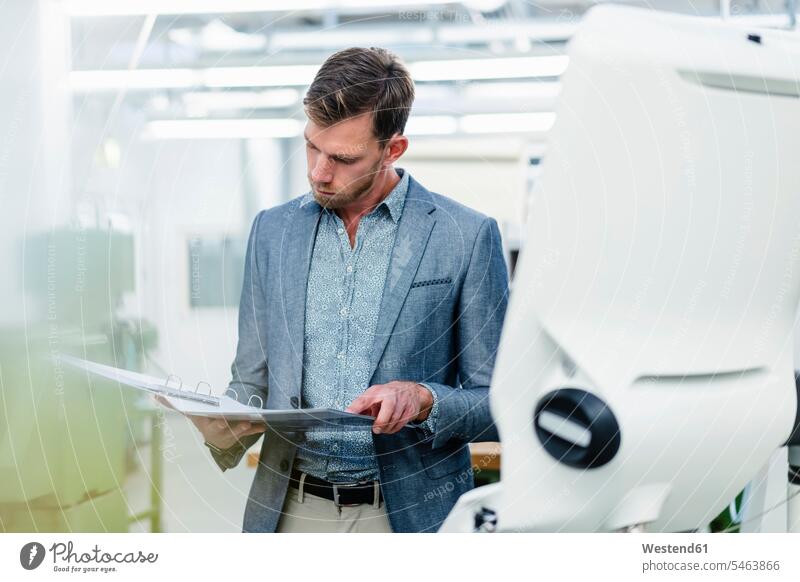 Male professional looking at plan in file document at factory color image colour image indoors indoor shot indoor shots interior interior view Interiors Germany