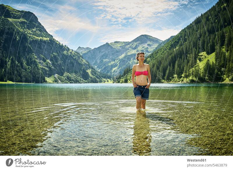Mature woman knee deep in Vilsalpsee against mountain range on sunny day color image colour image Austria outdoors location shots outdoor shot outdoor shots
