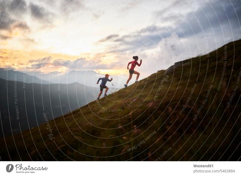 Man and woman running uphill in the mountains in the morning sports athletes Sportsman Sportsmen Sportspeople Sportsperson Accomplish Accomplishment Achieve