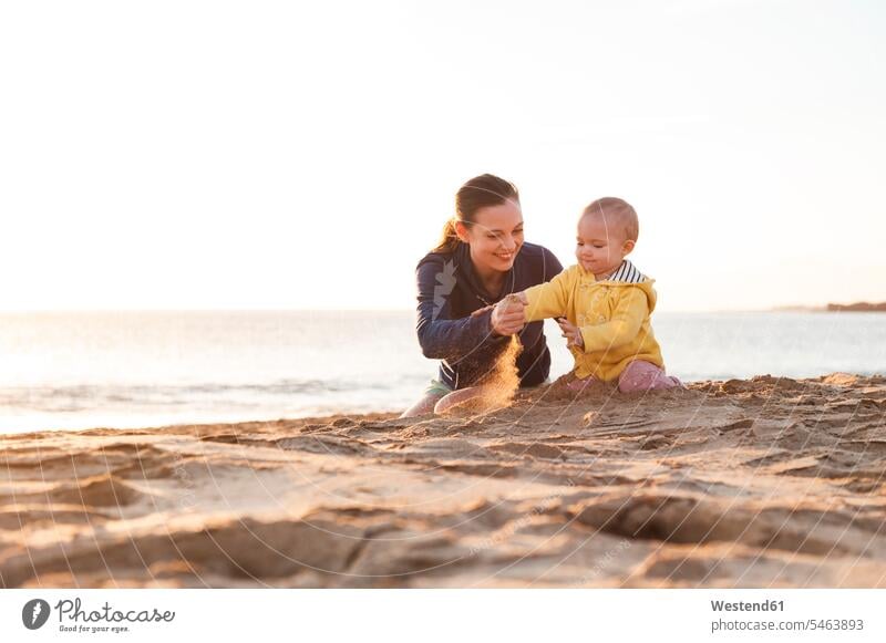 Mother playing with little daughter on the beach beaches baby infants nurselings babies mother mommy mothers ma mummy mama daughters people persons human being
