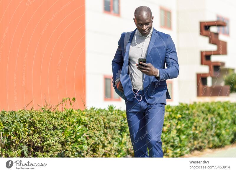 Businessman wearing blue suit listening music with earphones and smartphone Business man Businessmen Business men Smartphone iPhone Smartphones hearing