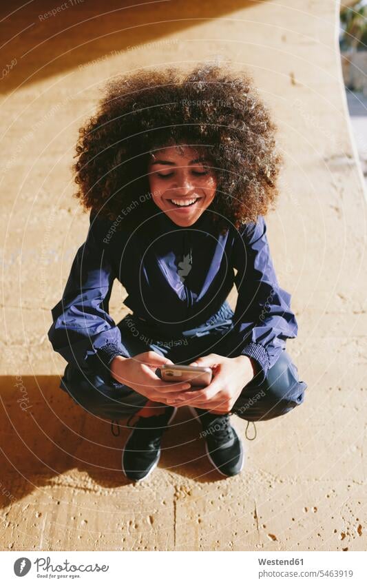 Stylish young woman wearing tracksuit and using cell phone outdoors human human being human beings humans person persons curl curled curls curly hair