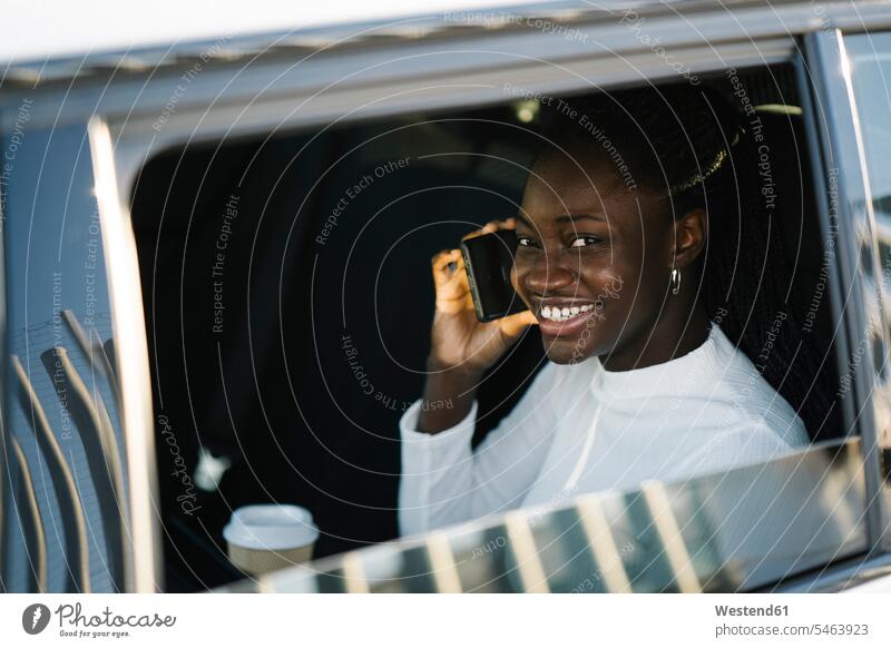 Smiling teenage girl on phone call seen through car window color image colour image outdoors location shots outdoor shot outdoor shots day daylight shot