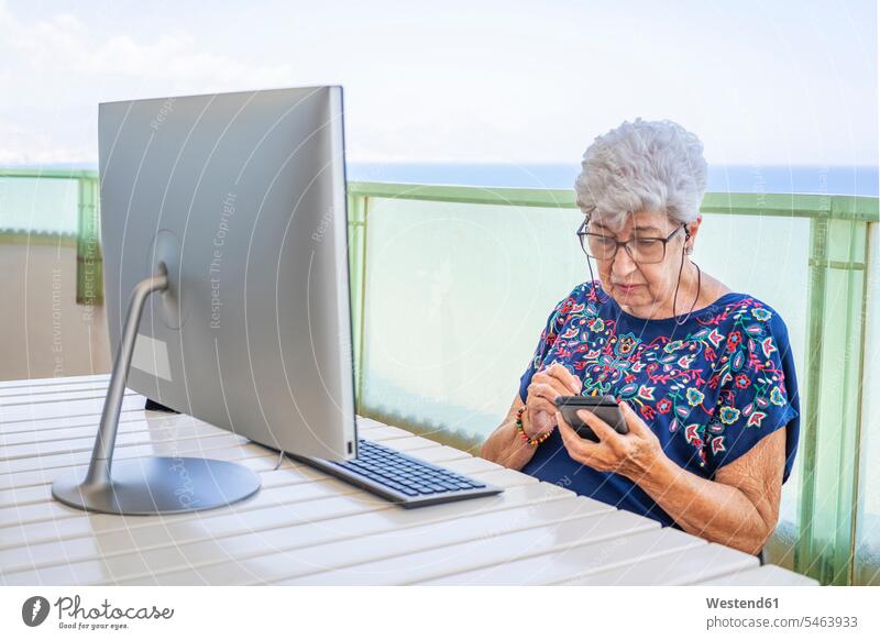 Senior woman using smartphone on the terrace Tables computers desktop computer Desktop Computers desktop PC personal computer personal computers