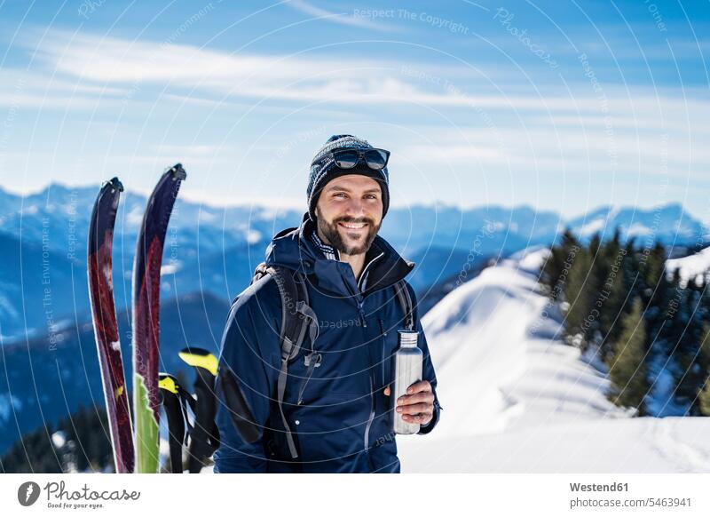 Germany, Bavaria, Brauneck, portrait of smiling man on a ski tour in winter in the mountains having a break men males portraits Ski Touring ski tours hibernal