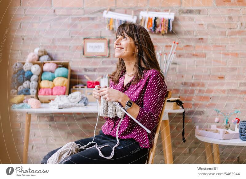 Smiling woman sitting on chair knitting smiling smile Seated chairs females women Adults grown-ups grownups adult people persons human being humans human beings