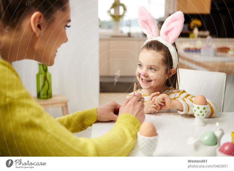 Girl with bunny ears and mother sitting at table with Easter eggs daughter daughters Rabbit Ears Bunny Ear Bunny Ears costume rabbit ears mommy mothers ma mummy