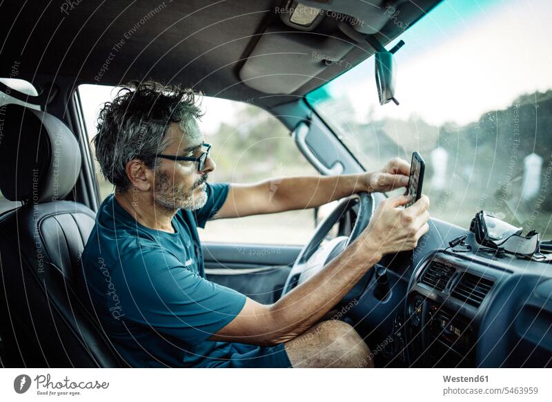 Mature man sitting sitting in his off-road vehicle checking his smartphone human human being human beings humans person persons caucasian appearance
