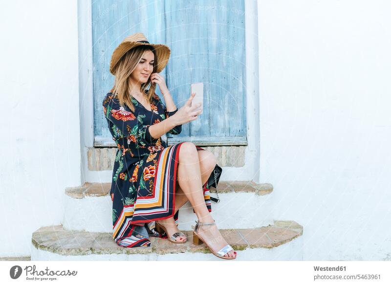 Spain, Cadiz, Vejer de la Frontera, fashionable woman taking selfie with mobile phone in front of blue door females women Selfie Selfies Smartphone iPhone