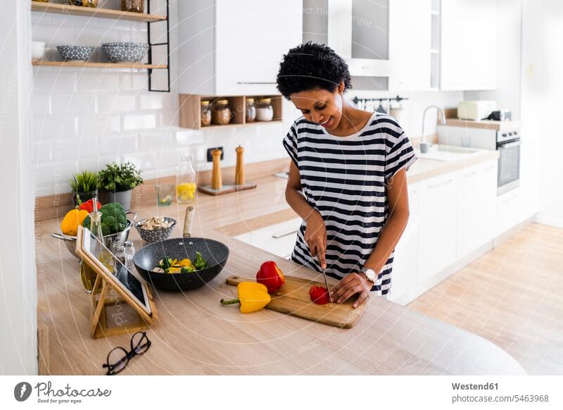 Young woman with tablet cooking in kitchen at home cutting vegetables human human being human beings humans person persons celibate celibates singles