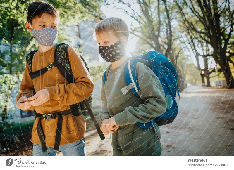 Brothers wearing protective face mask while walking in public park on sunny day color image colour image outdoors location shots outdoor shot outdoor shots