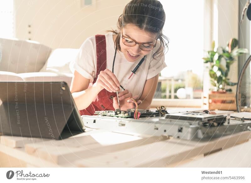 Young woman working on computer equipment at home next to tablet Germany Competence Skill attention attentive paying attention mounting assembling digitizer