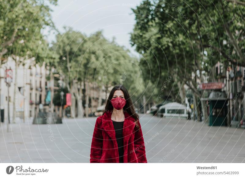 Portrait of woman wearing red face mask and jacket standing on empty street in city, Barcelona, Spain color image colour image outdoors location shots