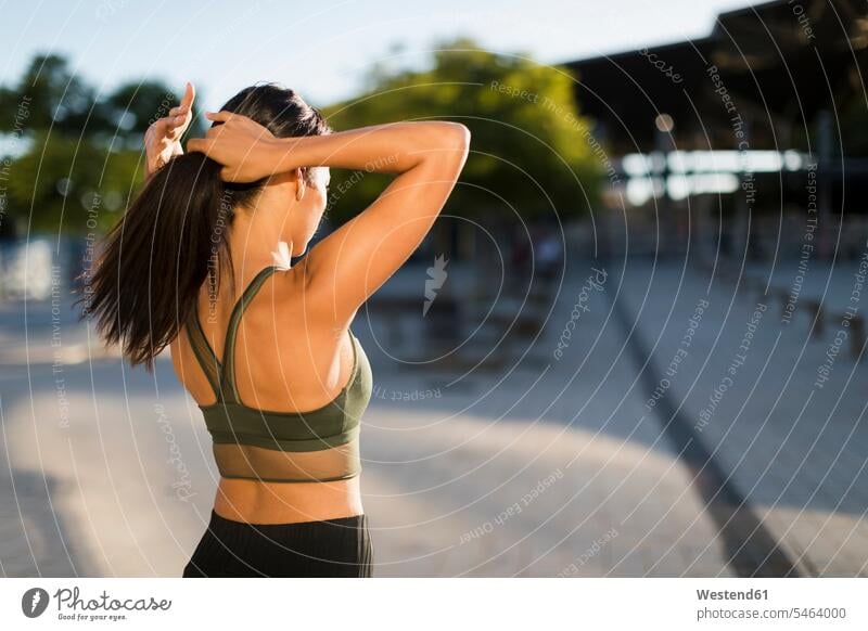 Sporty young woman doing her hair in the city females women sportive sporting sporty athletic break town cities towns people persons human being humans