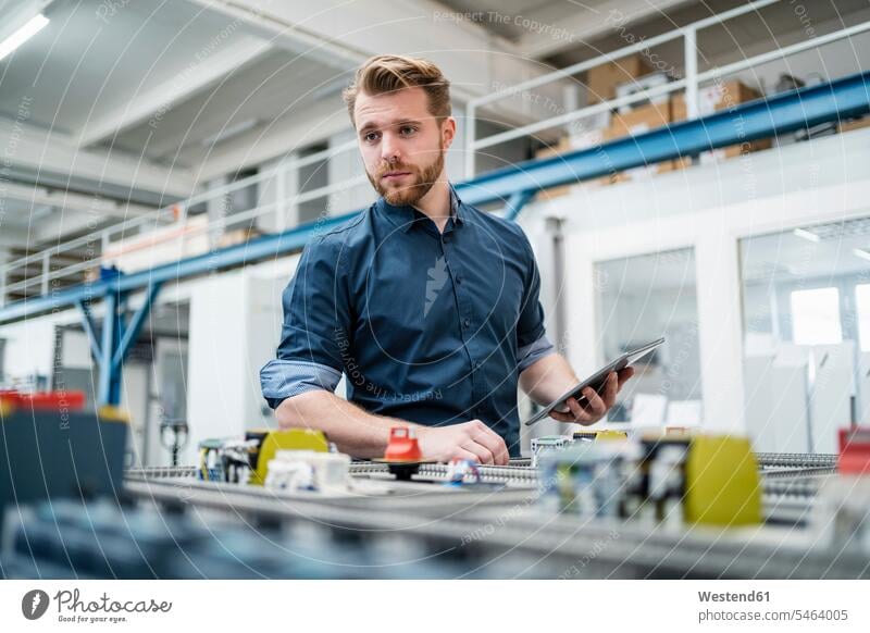 Young man using a tablet in a factory Occupation Work job jobs profession professional occupation business life business world business person businesspeople