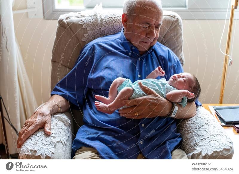 Grandfather sitting in an armchair holding a newborn baby generation chairs Arm Chair Arm Chairs armchairs relax relaxing asleep relaxation Secure closeness