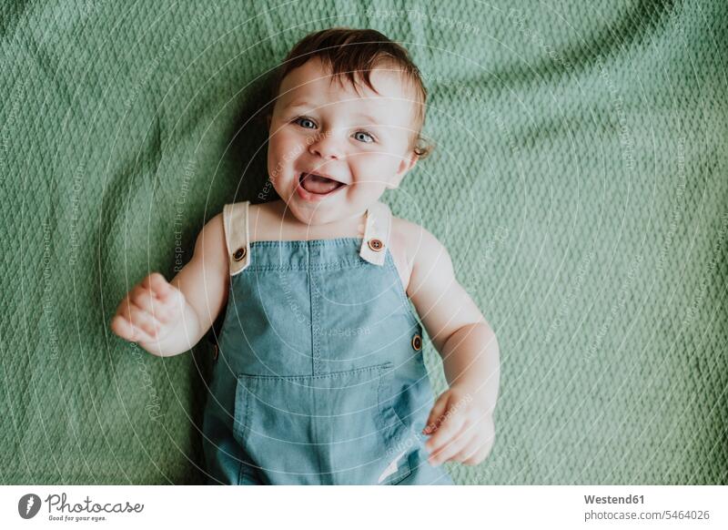 Close-up of cute baby girl laughing while lying on blanket at home color image colour image Spain leisure activity leisure activities free time leisure time