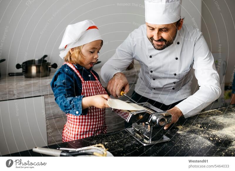 Father and daughter making homemade pasta with pasta machine in kitchen at home Chefs cook cooks hold learn smile delight enjoyment Pleasant pleasure