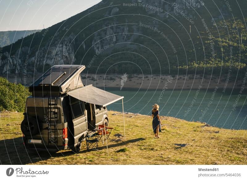 Woman looking at lake while standing by camper van during vacation color image colour image outdoors location shots outdoor shot outdoor shots day daylight shot