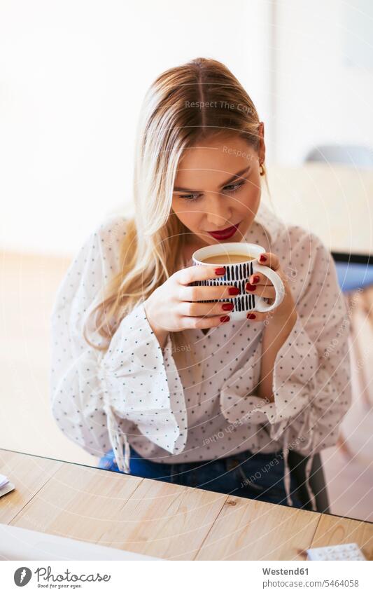 Young woman working in office, taking a break, drinking coffee blond blond hair blonde hair businesswoman businesswomen business woman business women At Work