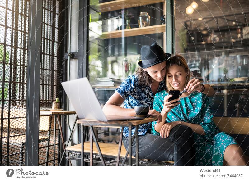 Artist couple sitting in cafe and checking the young woman's smartphone in love Affection Affectionate Smartphone iPhone Smartphones Love loving twosomes