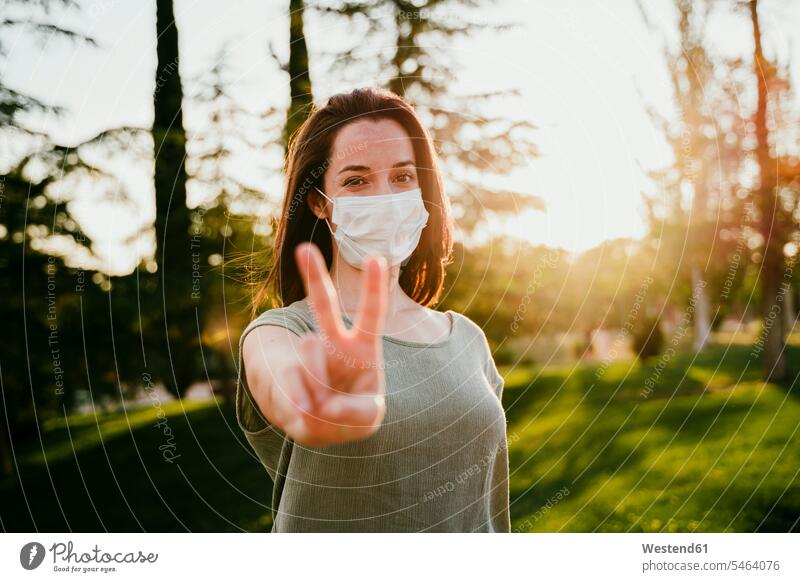 Portrait of woman wearing protective mask in nature showing victory sign country country side countryside free time leisure time gesturing healthy Lifestyle
