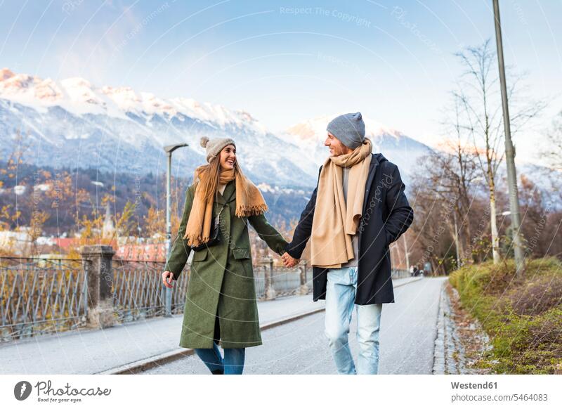 Austria, Innsbruck, happy young couple strolling together hand in hand at winter time Wintertime Winter time twosomes partnership couples walking taking a walk