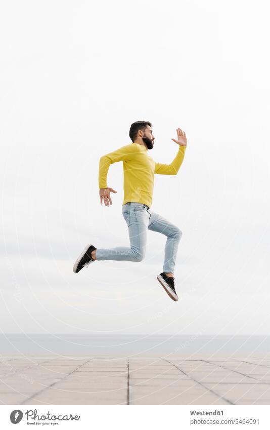 Carefree young man jumping on footpath against white wall color image colour image Spain leisure activity leisure activities free time leisure time