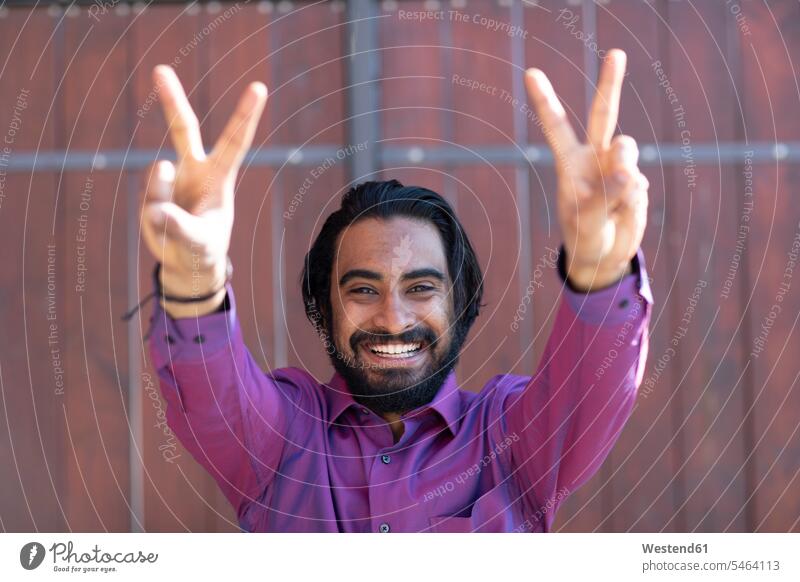 Young smiling man making peace sign in front of a gate Occupation Work job jobs profession professional occupation engineering technologies technicians shirts