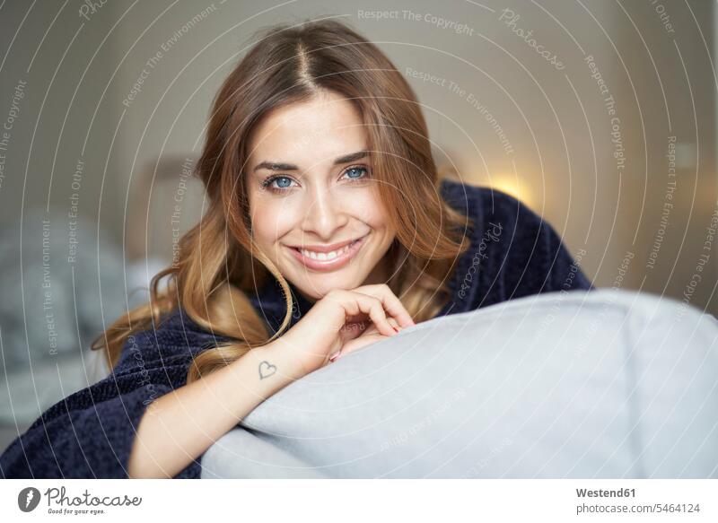 Portrait of smiling young woman on couch females women settee sofa sofas couches settees smile portrait portraits Adults grown-ups grownups adult people persons