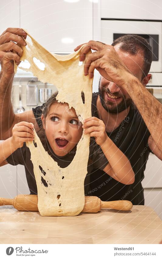 Father and daughter playing with pizza dough on table in kitchen color image colour image Spain leisure activity leisure activities free time leisure time