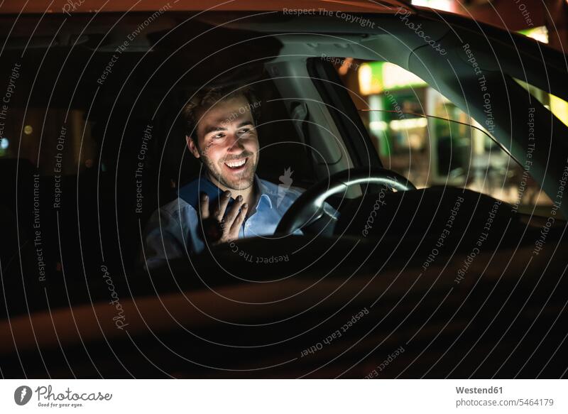 Happy young man using cell phone in car at night Germany call telephone call Phone Call listening wireless Wireless Connection Wireless Technology