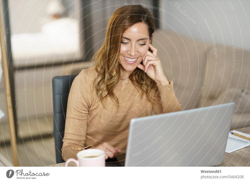 Businesswoman smiling while working on laptop at home color image colour image indoors indoor shot indoor shots interior interior view Interiors day