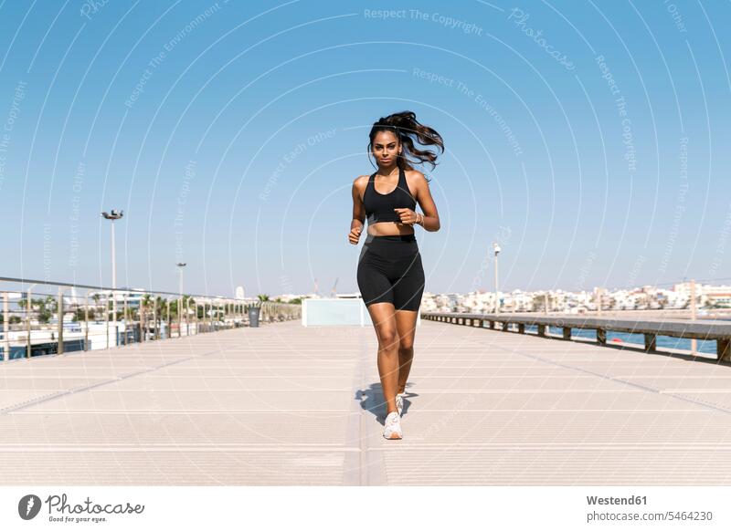 Woman running at harbor against clear sky during sunny day color image colour image outdoors location shots outdoor shot outdoor shots daylight shot