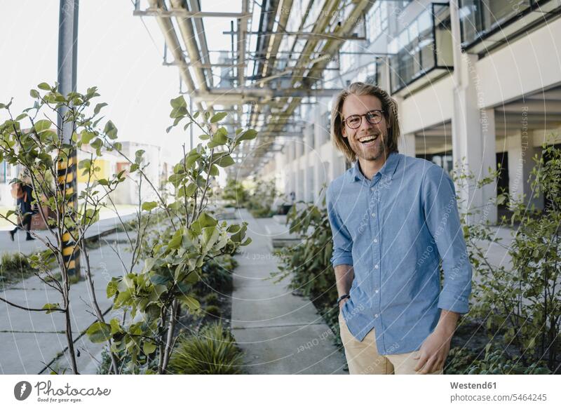 Happy young man standing on pavement surrounded by plants human human being human beings humans person persons caucasian appearance caucasian ethnicity european