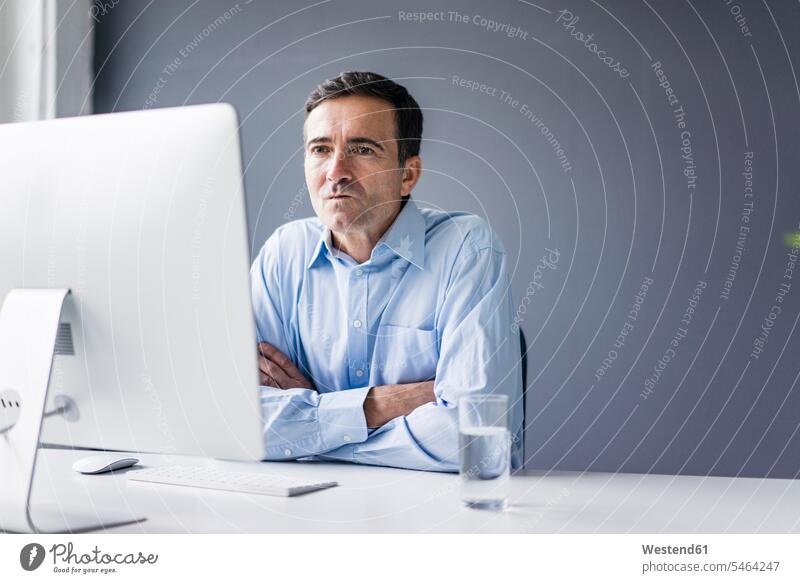 Serious businessman sitting at desk in office looking at computer screen Computer Monitor computer screens Computer Monitors Businessman Business man