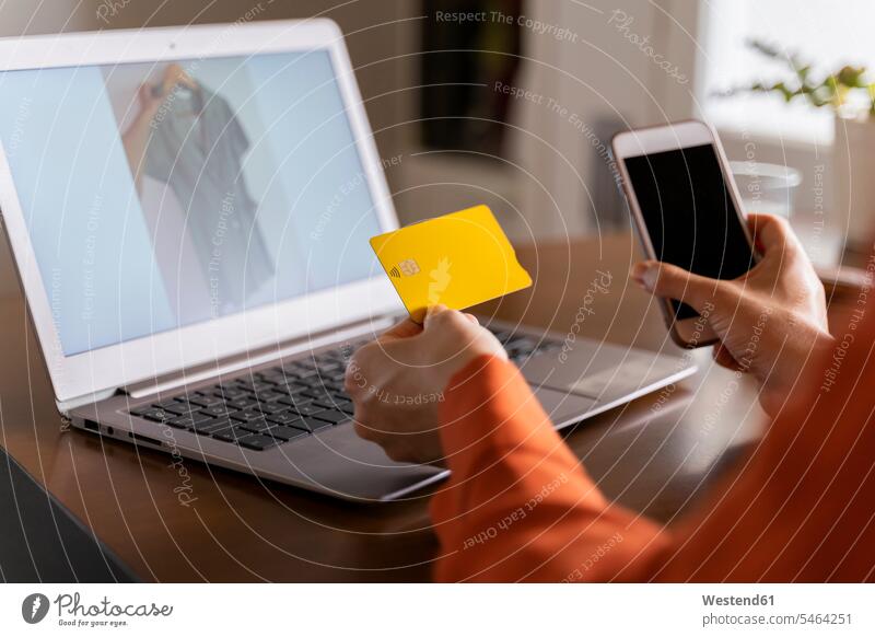 Cropped image of businesswoman with credit card using smart phone while purchasing online at home color image colour image indoors indoor shot indoor shots