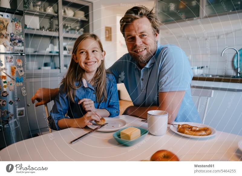 Portrait of father and daughter at home sitting at breakfast table looking at camera looking to camera looking at the camera Eye Contact daughters happiness