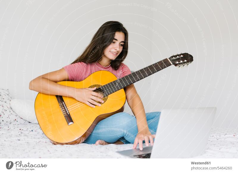 Woman learning guitar online at home in bedroom color image colour image indoors indoor shot indoor shots interior interior view Interiors day daylight shot