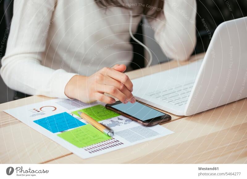 Close-up of woman with document, cell phone and laptop at desk in office paper documents papers mobile phone mobiles mobile phones Cellphone cell phones desks