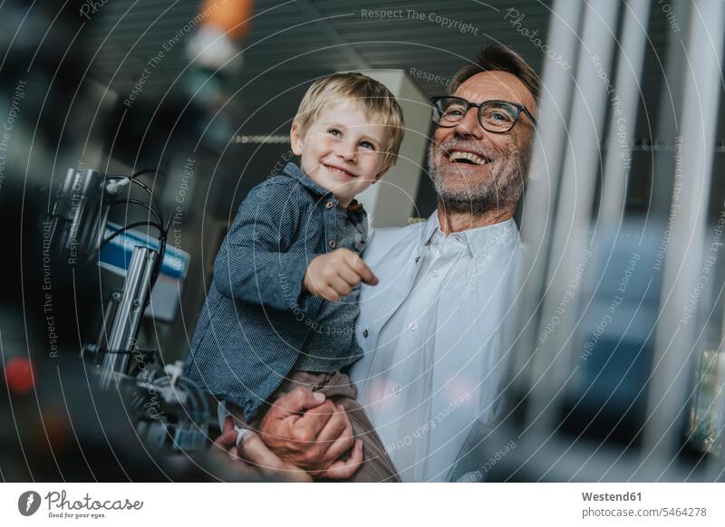 Happy scientist father carrying son while standing in laboratory at factory color image colour image indoors indoor shot indoor shots interior interior view