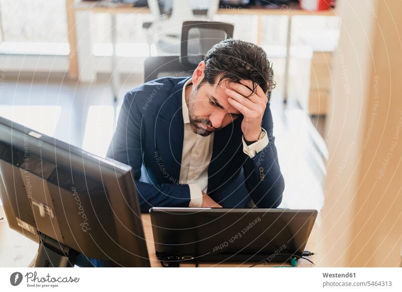 Frustrated businessman sitting at desk in office Occupation Work job jobs profession professional occupation business life business world business person