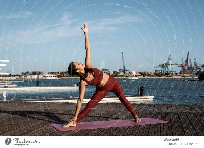 Asian woman practicing yoga at harbour, triangle pose human human being human beings humans person persons Asians Chinese 1 one person only only one person