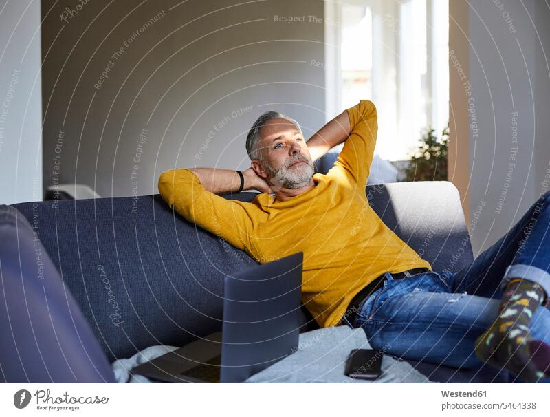 Mature man relaxing on couch at home human human being human beings humans person persons celibate celibates singles solitary people solitary person jumper