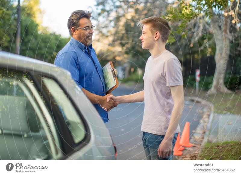 Learner driver and instructor shaking hands at car learner driver student driver Handclasp Handclap automobile Auto cars motorcars Automobiles driving school
