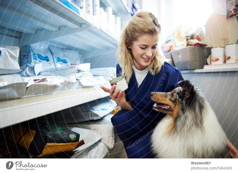 Young woman taking food for a dog from shelf in veterinary surgery veterinary practice veterinary office veterinary practices vet's surgery vet's office