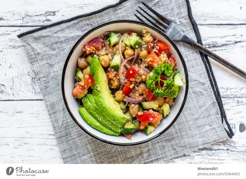 Bowl of vegetarian quinoa salad with chick-peas, avocado, cucumber, tomato, onion and parsley overhead view directly above top view close-up close up closeup