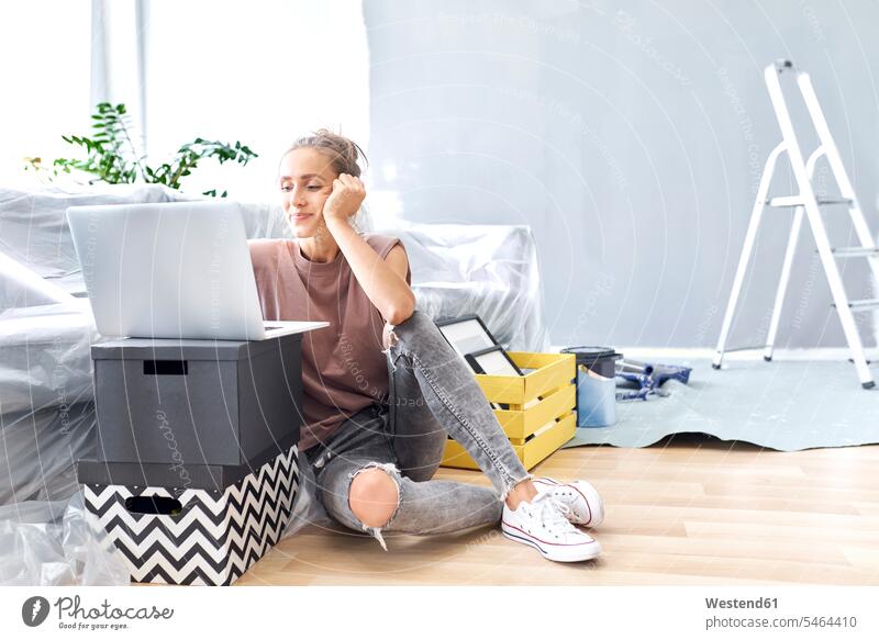 Smiling woman using laptop while sitting by sofa at home color image colour image indoors indoor shot indoor shots interior interior view Interiors day