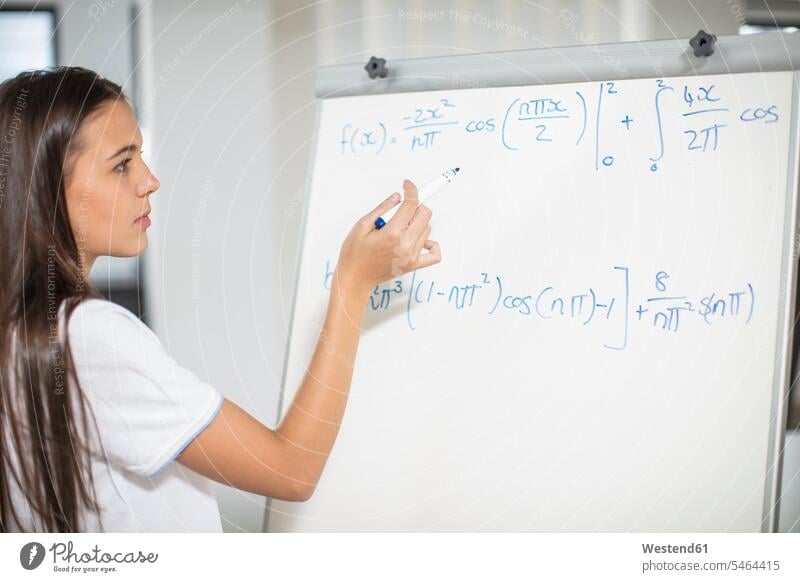 Teenage girl writing formula on whiteboard Classroom class rooms Schoolroom classrooms write school schools white board Teenager Teens teenagers school class